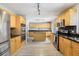 Spacious kitchen featuring stainless steel appliances, black countertops, and light wood cabinets and flooring at 14160 82Nd Ter, Seminole, FL 33776