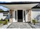 Close-up of the front door with stone accents, sidelights, stylish lighting, and brick pathway at 5028 School Rd, Land O Lakes, FL 34638