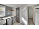 Kitchen with gray cabinets, stainless steel dishwasher, quartz counters, and view to hallway at 5028 School Rd, Land O Lakes, FL 34638