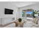 Living room features a TV, modern console, sliding glass doors to a balcony, and neutral-colored furniture at 1940 Hawaii Ne Ave, St Petersburg, FL 33703