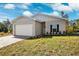 Beige house with white garage door and landscaping at 6454 Freeport Dr, Spring Hill, FL 34608