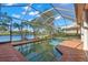 Screened pool area overlooking a serene lake, enhanced by palm trees and clear blue skies at 1160 Darlington Oak Ne Dr, St Petersburg, FL 33703