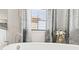 Close-up of a bathtub faucet in front of a window with natural light and decorative curtains at 2378 Whittler Br, Odessa, FL 33556