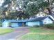 Blue house with a two-car garage nestled under lush tree coverage at 8201 Sunny Vale Pl, Tampa, FL 33615