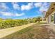 Large backyard overlooking the water and lush green landscape with a blue sky full of puffy clouds at 945 Bayshore Dr, Tarpon Springs, FL 34689