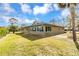 Exterior view of home featuring large windows and a luscious lawn with water views and palm trees at 945 Bayshore Dr, Tarpon Springs, FL 34689