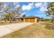 Two-car garage featuring wood doors and stone accents, set against a lush green lawn at 945 Bayshore Dr, Tarpon Springs, FL 34689