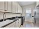 Modern laundry room with sleek black countertops, white cabinets, stainless steel washer and dryer, and natural light at 4825 Benito Ct, Bradenton, FL 34211