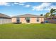 Backyard view of single-story home with well-maintained lawn and neutral-toned exterior at 1789 Broad Winged Hawk Dr, Ruskin, FL 33570