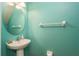 Small bathroom with pedestal sink, oval mirror, and teal walls at 5162 Bay Isle Cir, Clearwater, FL 33760