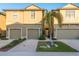Tan two-story townhome with a two-car garage and lush landscaping at 5162 Bay Isle Cir, Clearwater, FL 33760