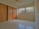 Simple bedroom with wood sliding doors and window at 105 Causeway Blvd, Belleair Beach, FL 33786