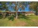 Backyard view of home showcasing a large tree, grass, and screened enclosure at 1669 Fry Ct, Dunedin, FL 34698