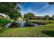 Community pond with fountain, lush landscaping, and homes in background at 1669 Fry Ct, Dunedin, FL 34698