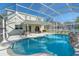 Inviting pool area with screened enclosure, patio furniture, and a waterfall feature at 12818 Royal George Ave, Odessa, FL 33556