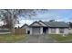 Street view of a one-story home featuring a gray color scheme, lawn, and front yard tree at 7908 E White Water Ct, Tampa, FL 33637