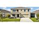 Two story house with tan exterior, two car garage, and landscaping at 16743 Carlton Pond St, Wimauma, FL 33598