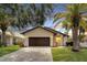 Front view of a single story home with a dark brown garage door and paver driveway at 6208 Spoonbill Dr, New Port Richey, FL 34652