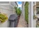 Narrow side yard with a gas grill, privacy fence, tropical plants, and walkway at 8272 Artisan Way, Seminole, FL 33777