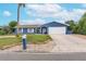 Blue house with white trim, a two-car garage, and a well-manicured lawn at 911 Silver Palm Way, Apollo Beach, FL 33572