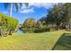 Spacious backyard with pond view, lush landscaping, and large trees at 16310 Ashington Park Dr, Tampa, FL 33647