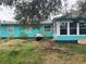 Turquoise single-story house with grill and enclosed back porch surrounded by a large unkept yard at 2716 49Th S St, Gulfport, FL 33707