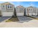 Three-story townhouses with gray siding, white garage doors, and gray paver driveways at 31496 Woodland Race Loop, Wesley Chapel, FL 33545