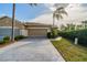 Front view of a tan house with a two-car garage and paved driveway at 2003 Acadia Greens Dr, Sun City Center, FL 33573
