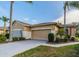 Tan single-Gathering home with attached garage, landscaping, and paved driveway at 2003 Acadia Greens Dr, Sun City Center, FL 33573