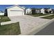 Two-car garage with a large brick paver driveway and a well-manicured lawn at 6625 Pebblebrooke Way, Zephyrhills, FL 33541