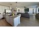 Open concept kitchen and living room with granite island, stainless steel appliances, and grey sofas at 6625 Pebblebrooke Way, Zephyrhills, FL 33541