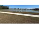 Community lake view with homes in the background and walking path at 6625 Pebblebrooke Way, Zephyrhills, FL 33541