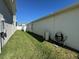 Landscaped side yard with grassy area and exterior utilities at 6625 Pebblebrooke Way, Zephyrhills, FL 33541