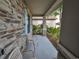 Covered front porch with stone details and two chairs at 14319 Italia Dr, Wimauma, FL 33598