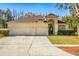 Tan house with three-car garage, lush landscaping, and a charming front entrance at 18214 Stillwell Ln, Tampa, FL 33647
