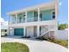 Two-story teal home with white trim, attached garage, and a walkway at 635 115Th Ave, Treasure Island, FL 33706