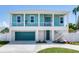 Two-story teal home with white trim, attached garage, and a walkway at 635 115Th Ave, Treasure Island, FL 33706