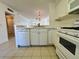 Bright kitchen boasts white cabinets, tile countertops, and a view into the living area at 2991 Flint S Dr # 77-D, Clearwater, FL 33759