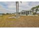 Property backyard featuring well-maintained lawn, palm trees, and an enclosed sunroom with expansive windows at 407 Blackhawk Cir, Sun City Center, FL 33573