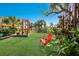 Landscaped backyard with red chairs and a pergola at 6119 Gnarled Oak Ln, Englewood, FL 34223