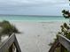 Wooden steps lead to a pristine beach with turquoise water at 6119 Gnarled Oak Ln, Englewood, FL 34223