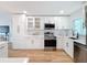Modern kitchen features white cabinetry, quartz countertops, stainless steel appliances, with hardwood floors at 1720 Flamingo Ln, Sun City Center, FL 33573