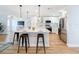 Bright kitchen features white cabinetry, quartz countertops, stainless steel appliances, island with bar seating and hardwood floors at 1720 Flamingo Ln, Sun City Center, FL 33573