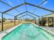 Screened-in pool with clear blue water, surrounded by an enclosure and lush landscaping at 1720 Flamingo Ln, Sun City Center, FL 33573
