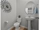 Stylish powder room with pedestal sink and round mirror at 2391 Summerlit St, Lutz, FL 33558
