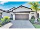 Tan two-story home with brown garage door at 17554 Holly Well Ave, Wimauma, FL 33598