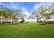Lush green courtyard with flowering trees and building in background at 3806 Gulf Of Mexico Dr # C211, Longboat Key, FL 34228