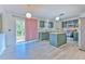 A sunlit kitchen with stainless appliances, island, green cabinets, and sliding glass door to the outside at 2359 Gimlet Ave, Spring Hill, FL 34608