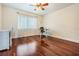 Bedroom with hardwood floors, ceiling fan, and window with white patterned curtain at 3360 Hickorywood Way, Tarpon Springs, FL 34688