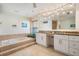 Bright bathroom featuring double sink with white cabinets and a large soaking tub at 3360 Hickorywood Way, Tarpon Springs, FL 34688
